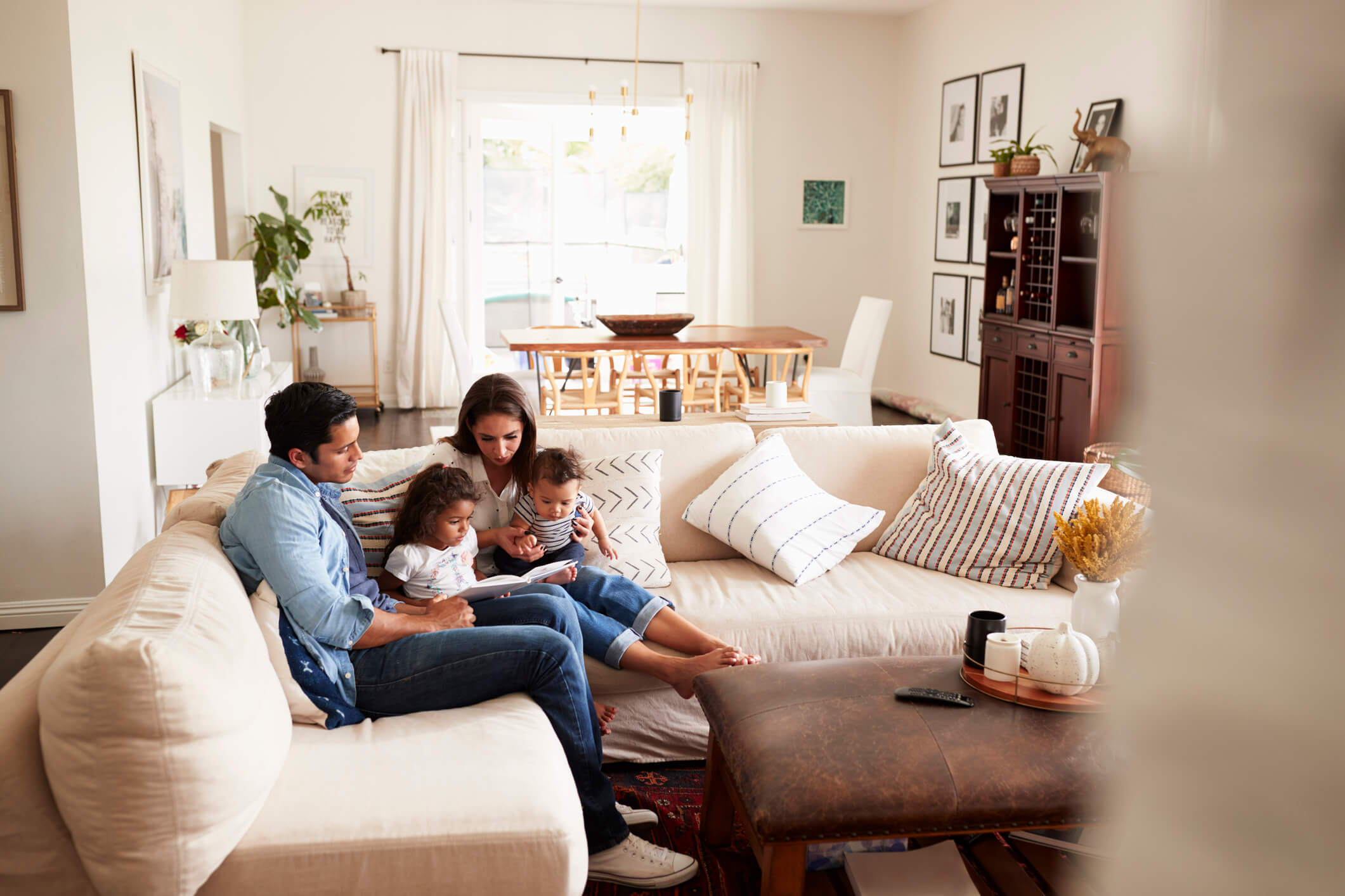A family reads to their young children in their comfortable home on their couch