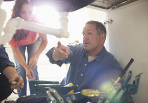 Plumber working on pipes under sink